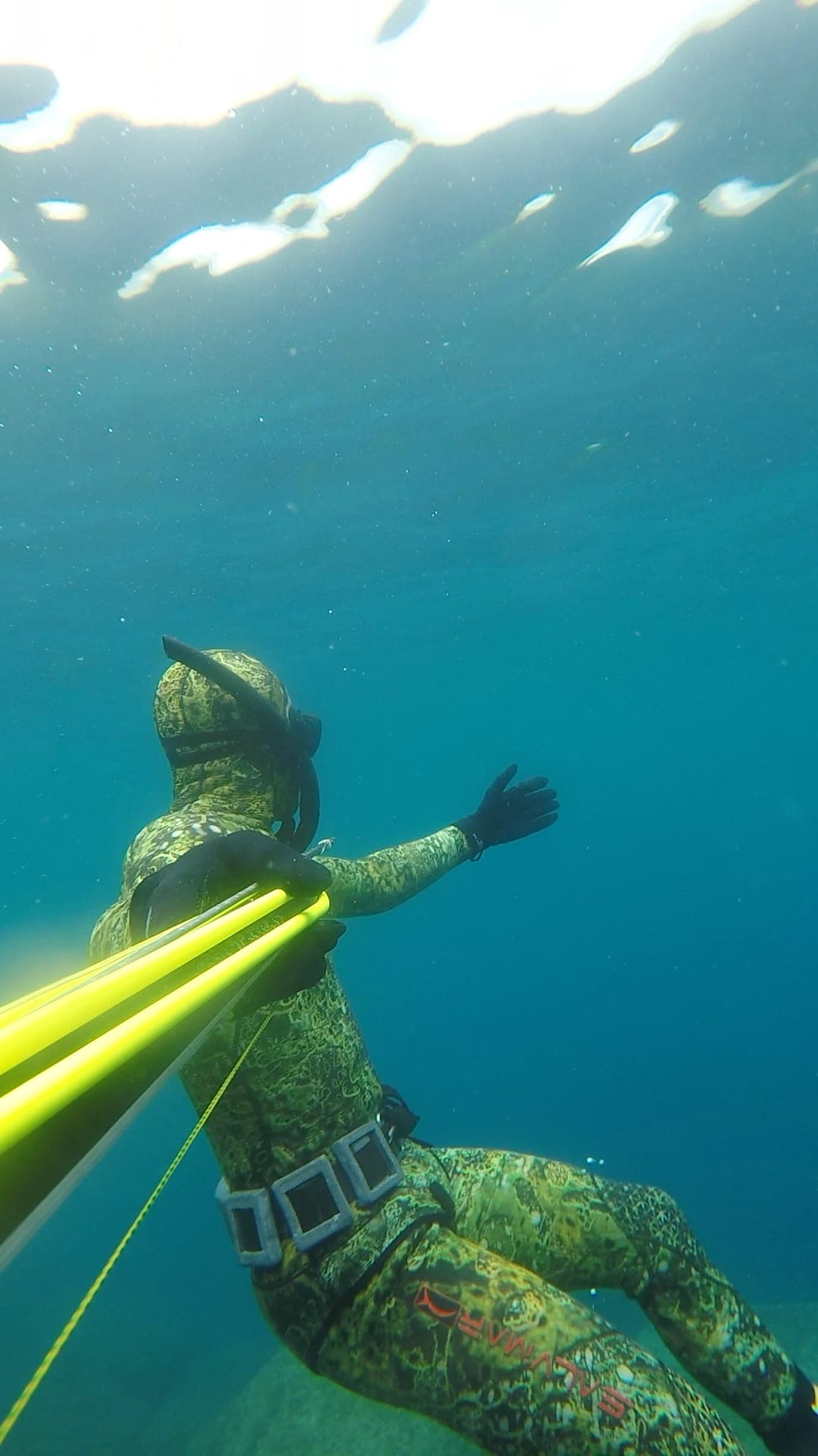Justin descend sous la surface, fusil en main